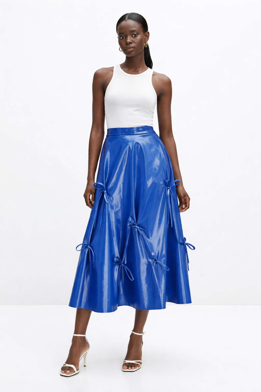 Woman wearing a white top and blue  KINGDOM OF DAUGHTERS skirt on a white background