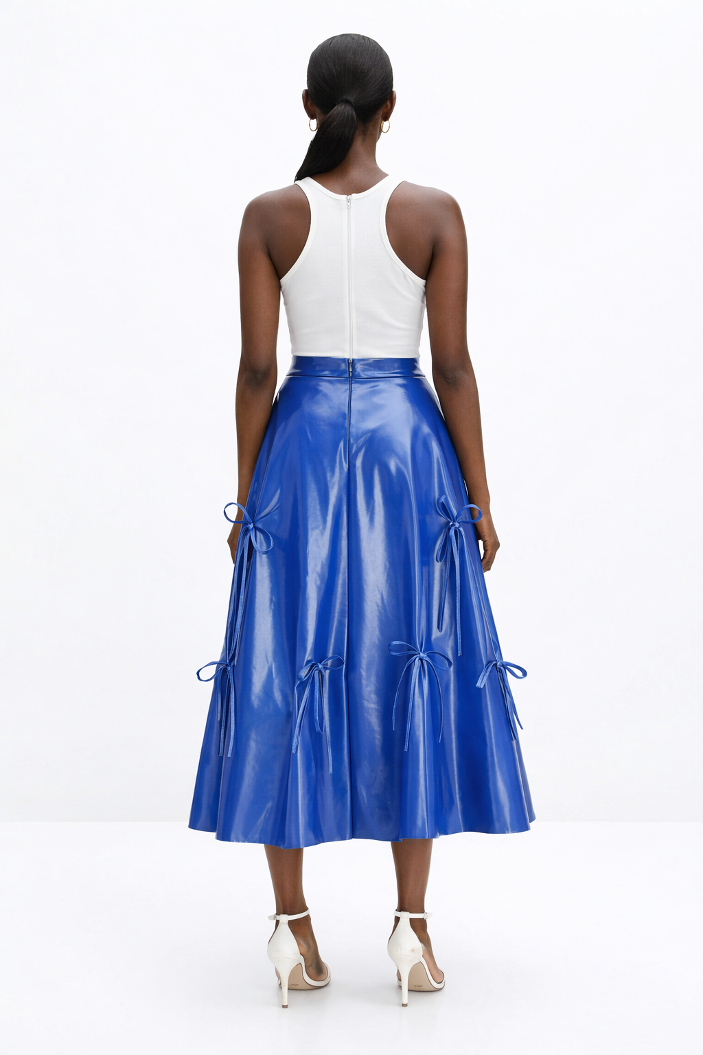 Woman wearing a white top and blue  KINGDOM OF DAUGHTERS skirt on a white background