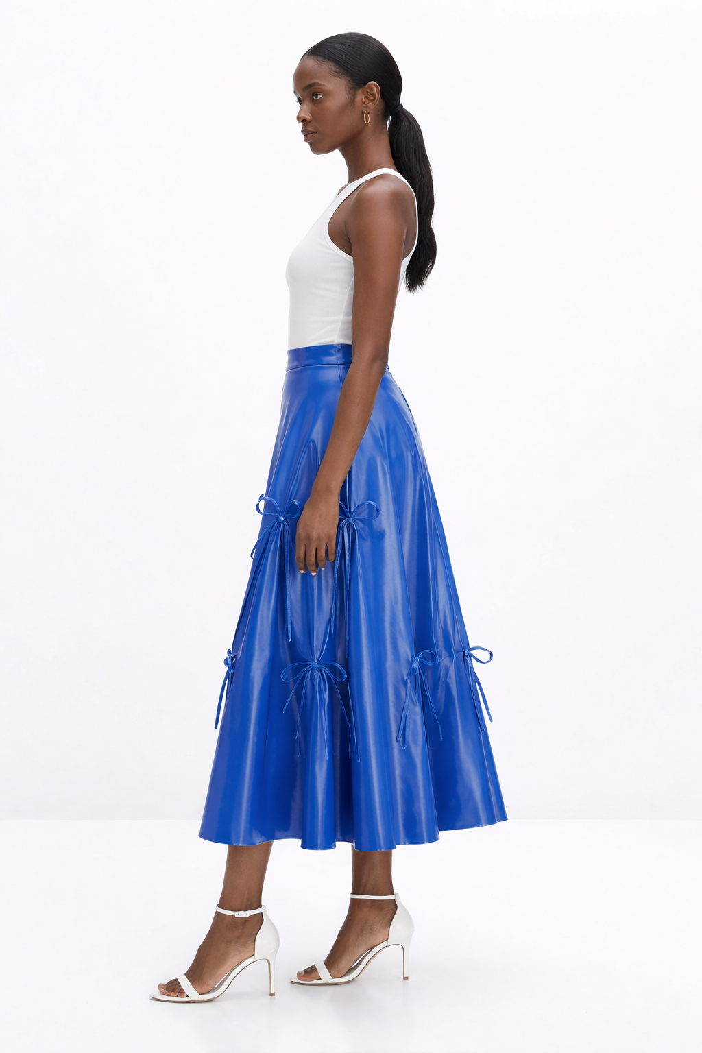 Woman wearing a white top and blue  KINGDOM OF DAUGHTERS skirt on a white background