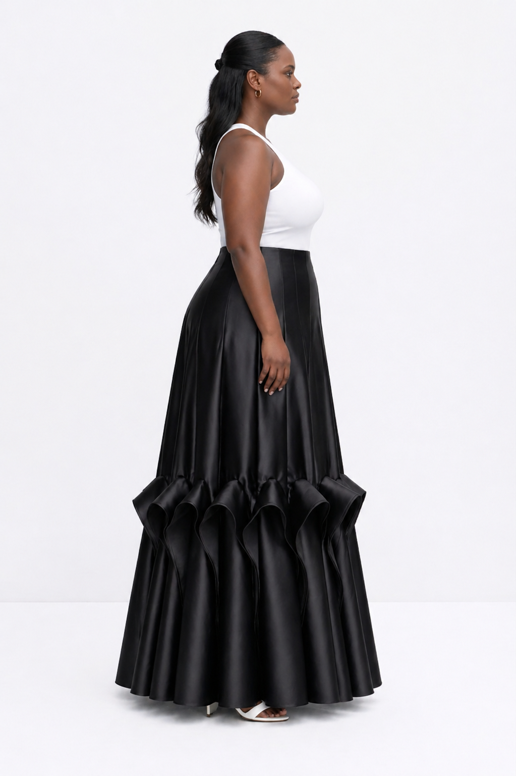 Woman wearing a black ruffled skirt and white top on a white background