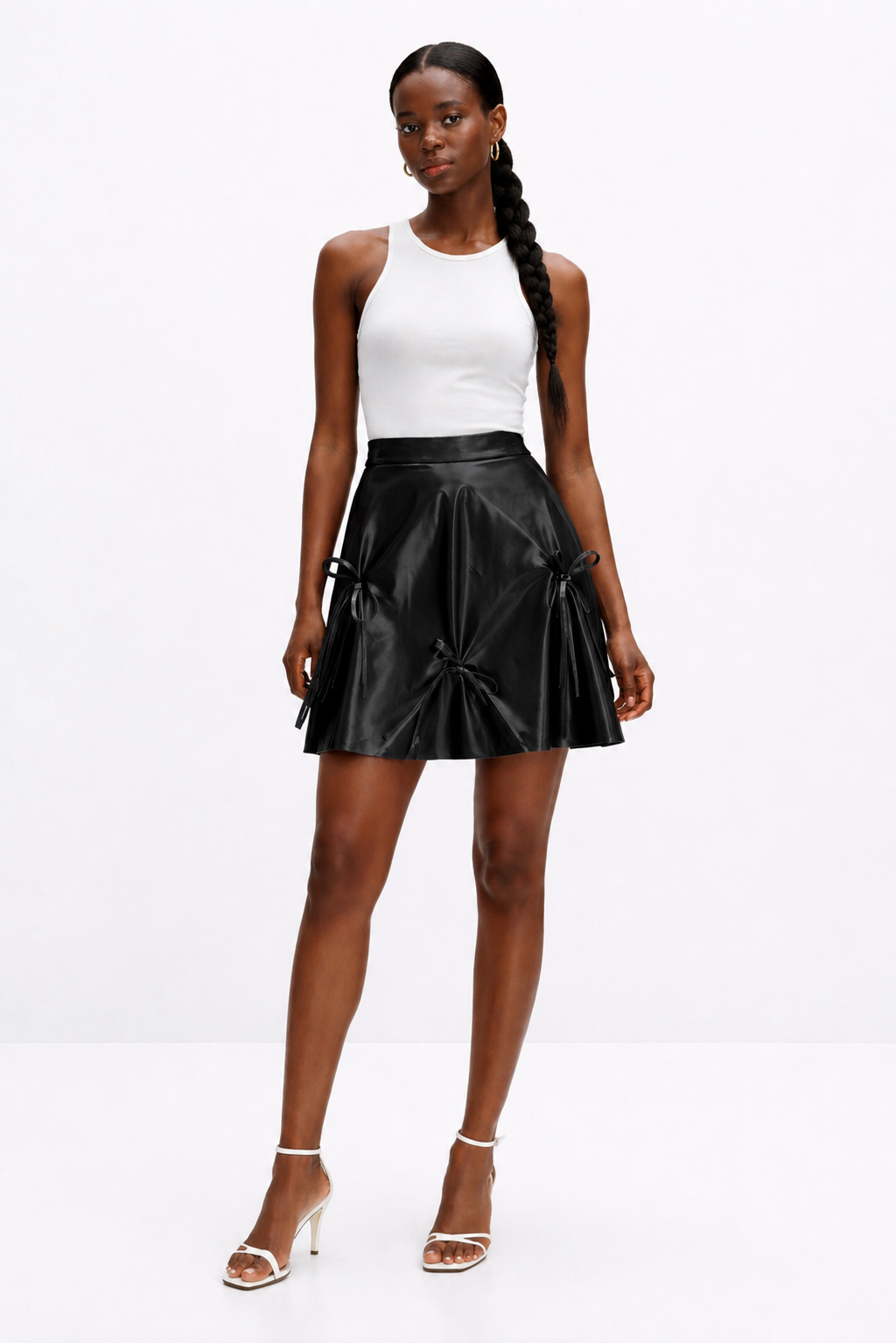 Woman wearing a black leather skirt and white top on a white background
