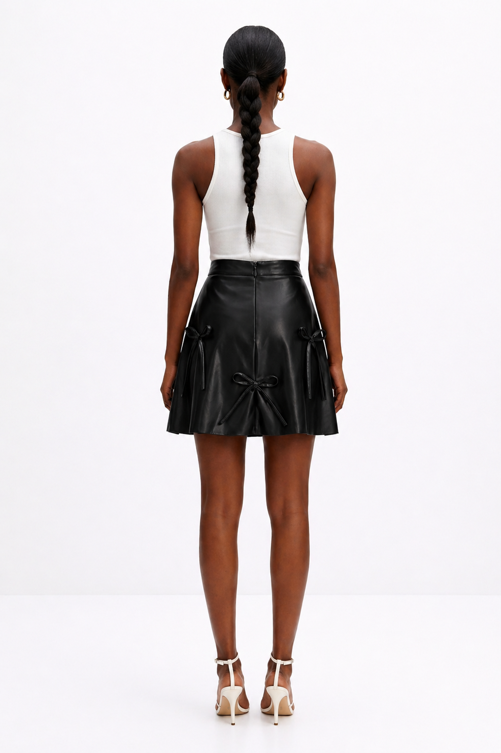 Person wearing a black leather skirt and white top on a white background