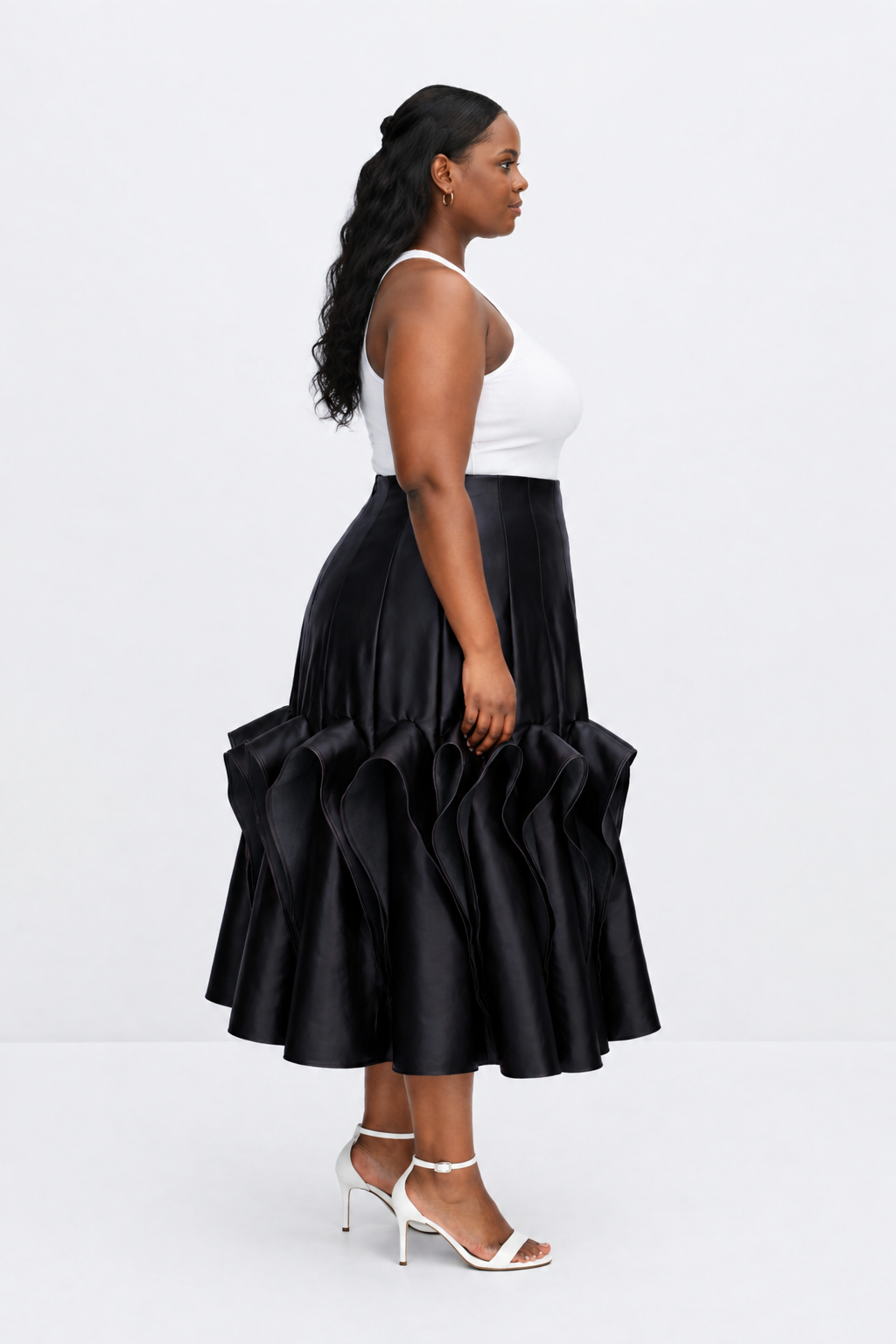 Woman wearing a black ruffled skirt and white top on a white background
