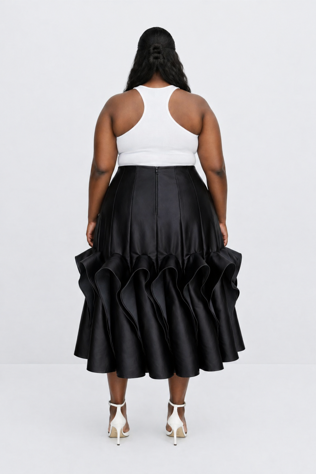 Person wearing a black ruffled skirt and white top on a white background
