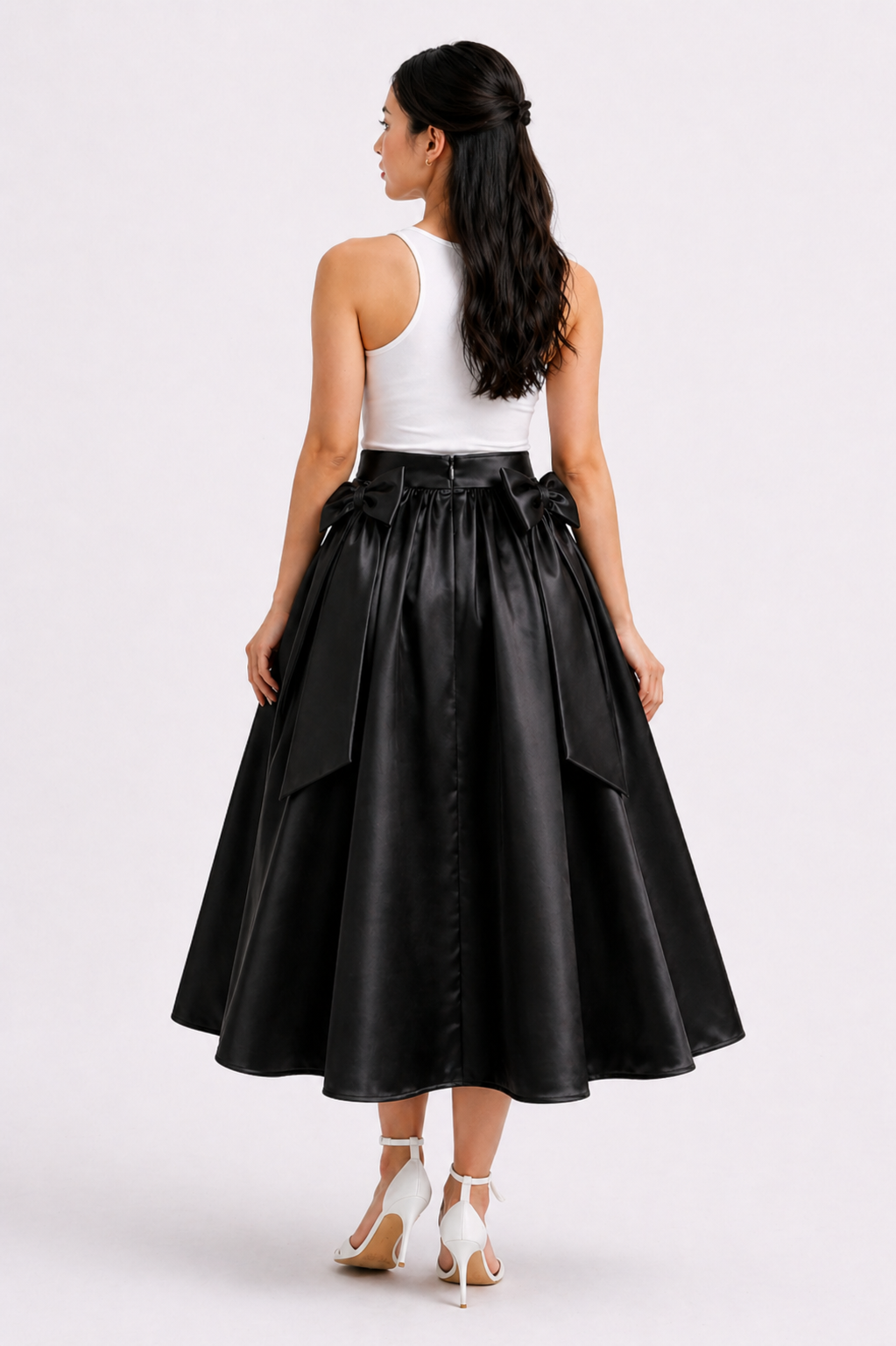 Woman wearing a black leather skirt and white top on a white background