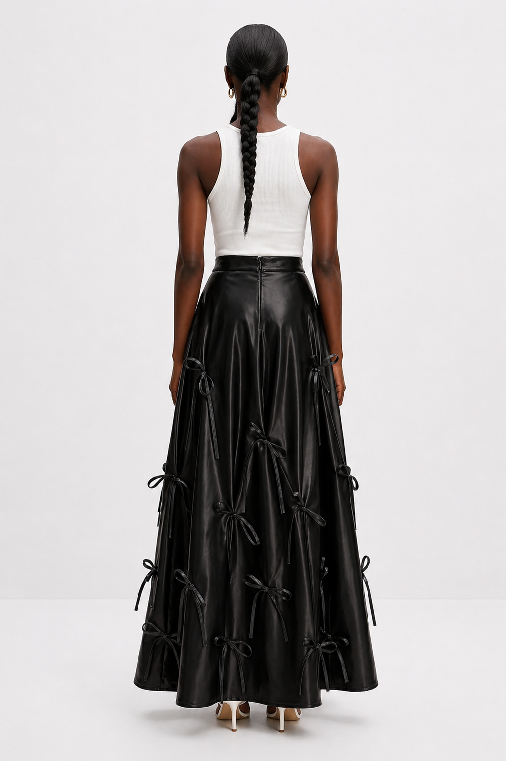 Person wearing a long black skirt with bow details on a white background
