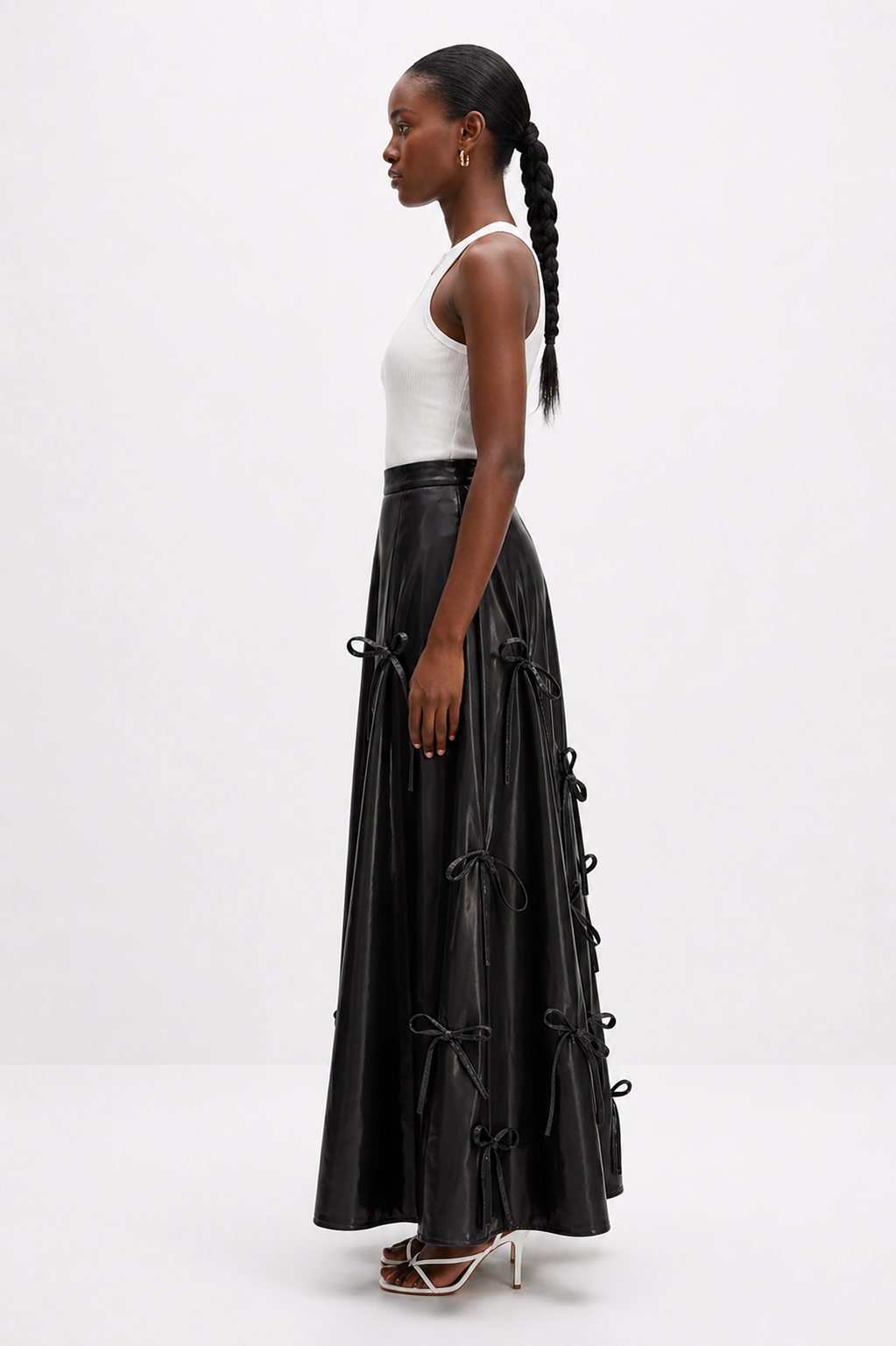 Woman wearing a black leather skirt with tie details on a white background