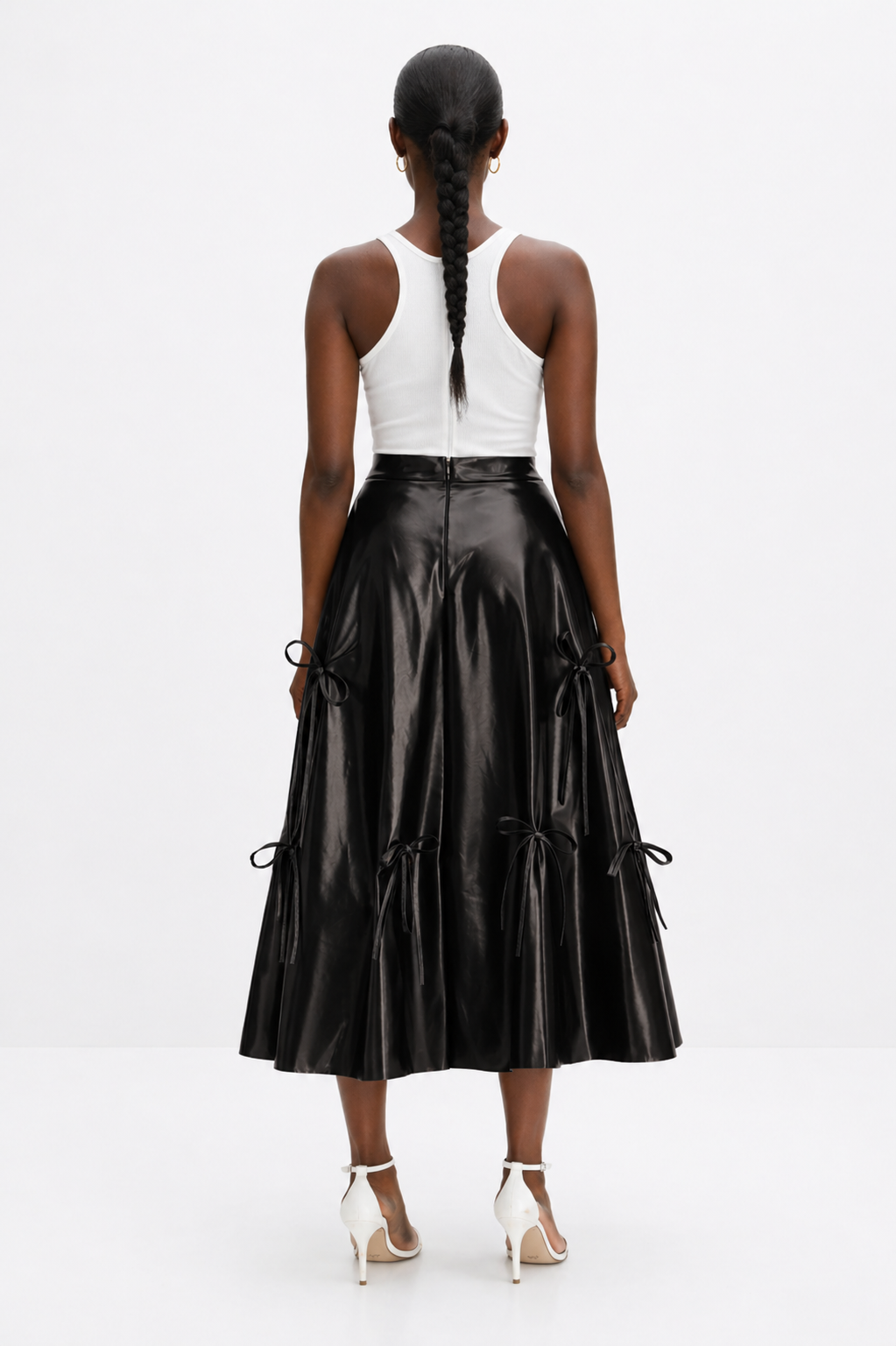 Woman wearing a black leather skirt and white top on a white background