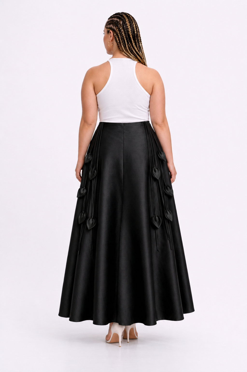 Woman wearing a white top and black skirt with ruffled details on a white background