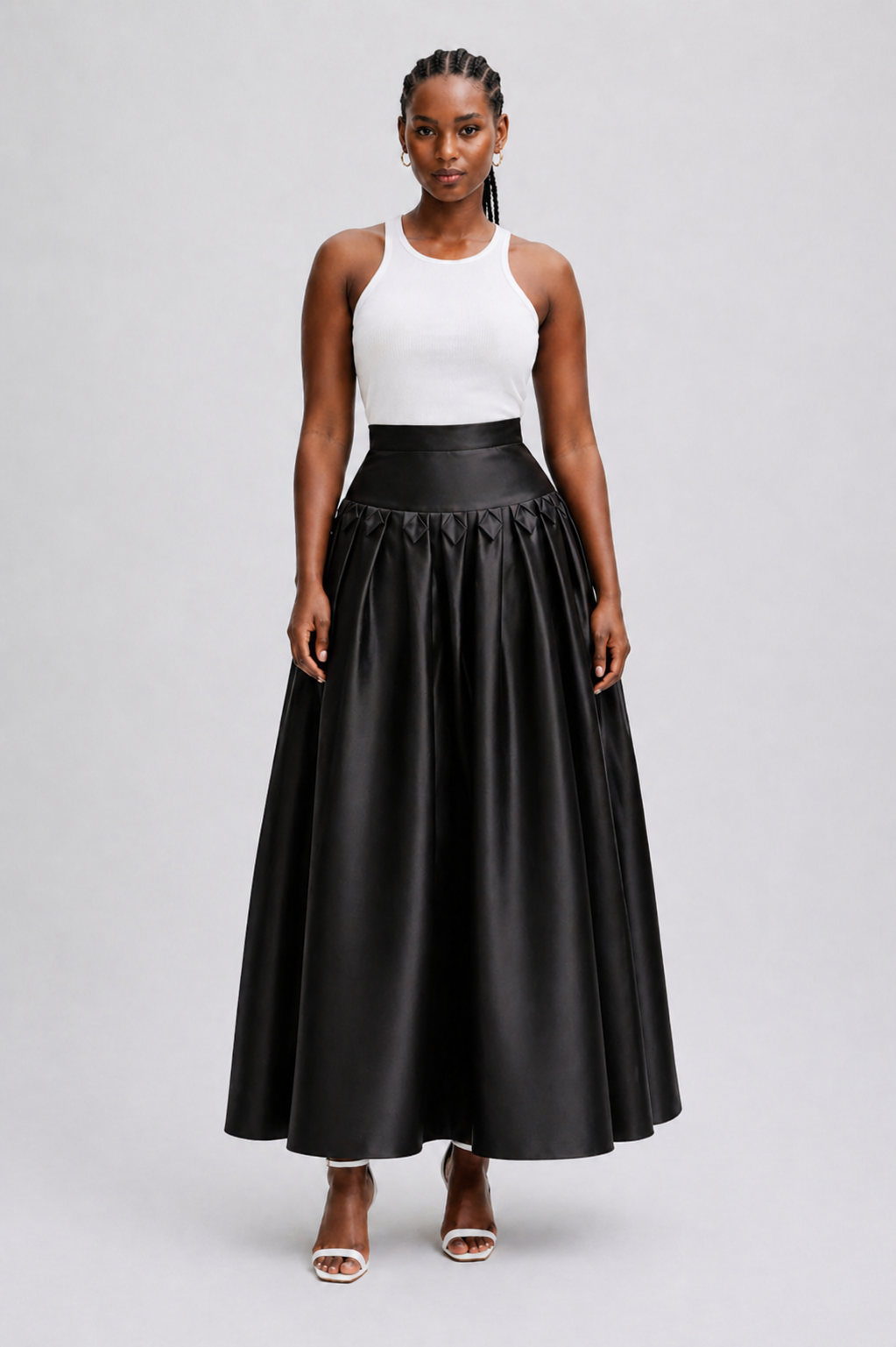 Woman wearing a white top and black full-length skirt on a light gray background
