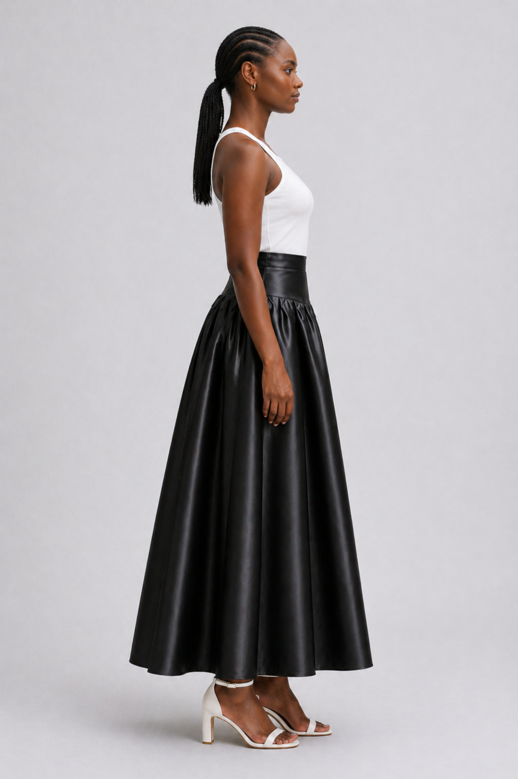 Woman wearing a black leather skirt and white top on a gray background