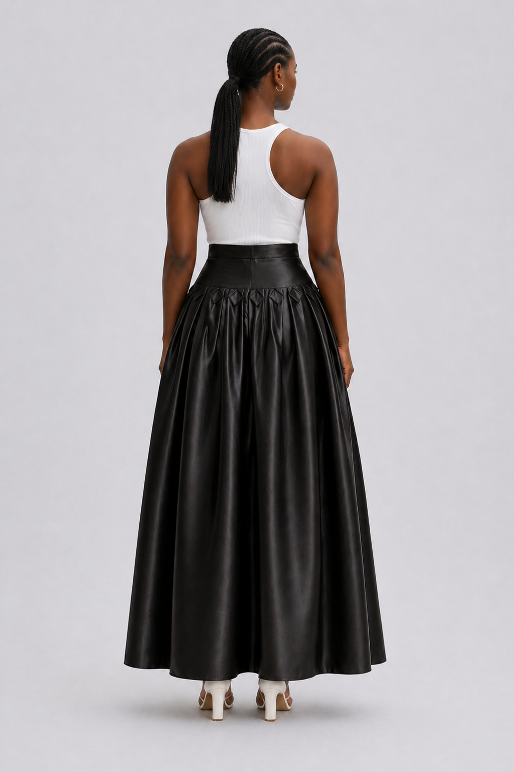 Person wearing a black leather skirt and white top on a gray background