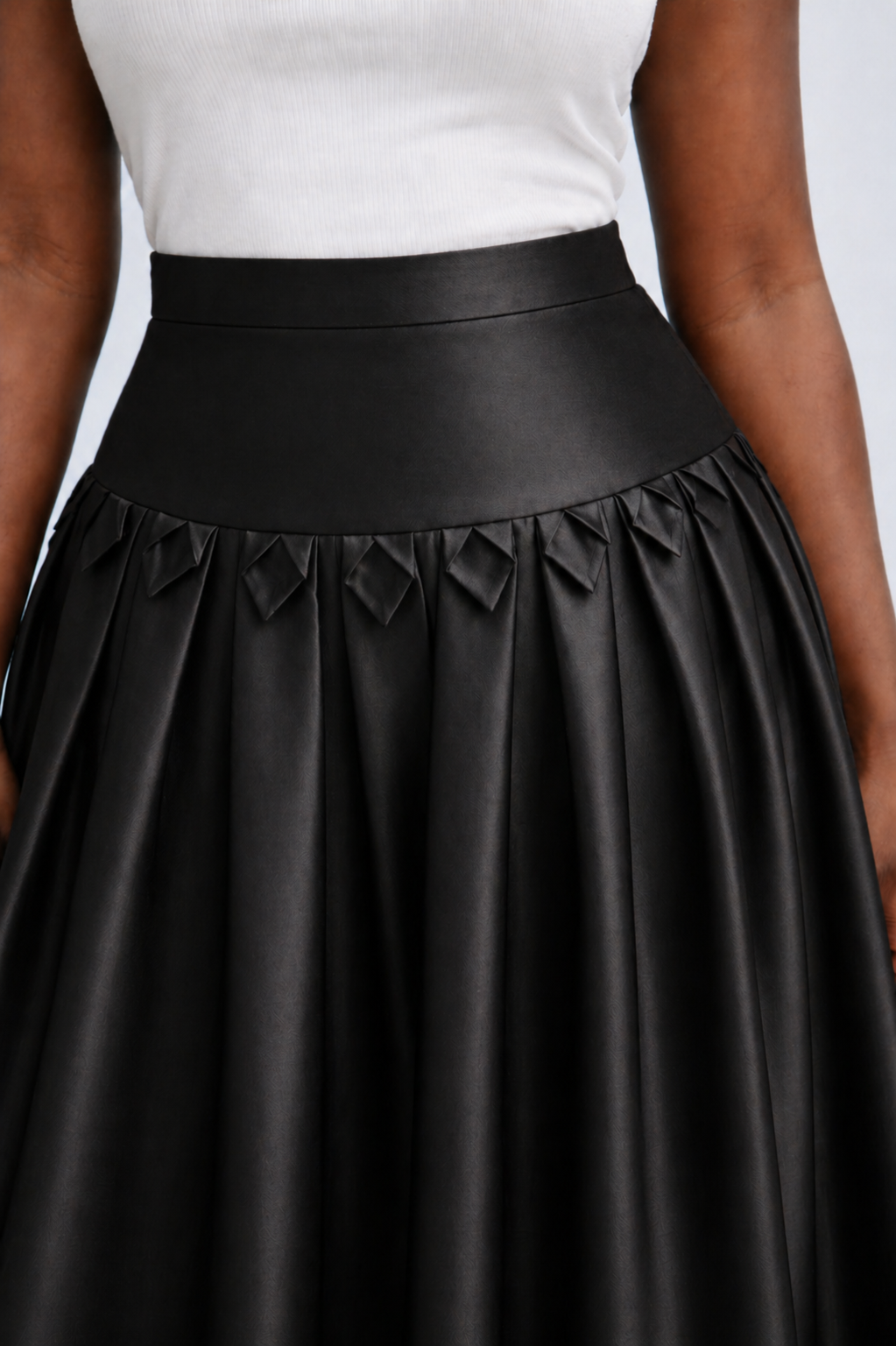 Black leather skirt with a white top on a neutral background