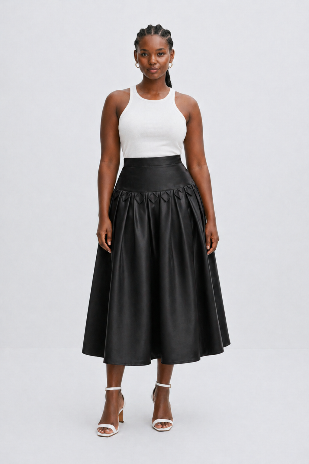 Woman wearing a black leather skirt and white top on a light gray background