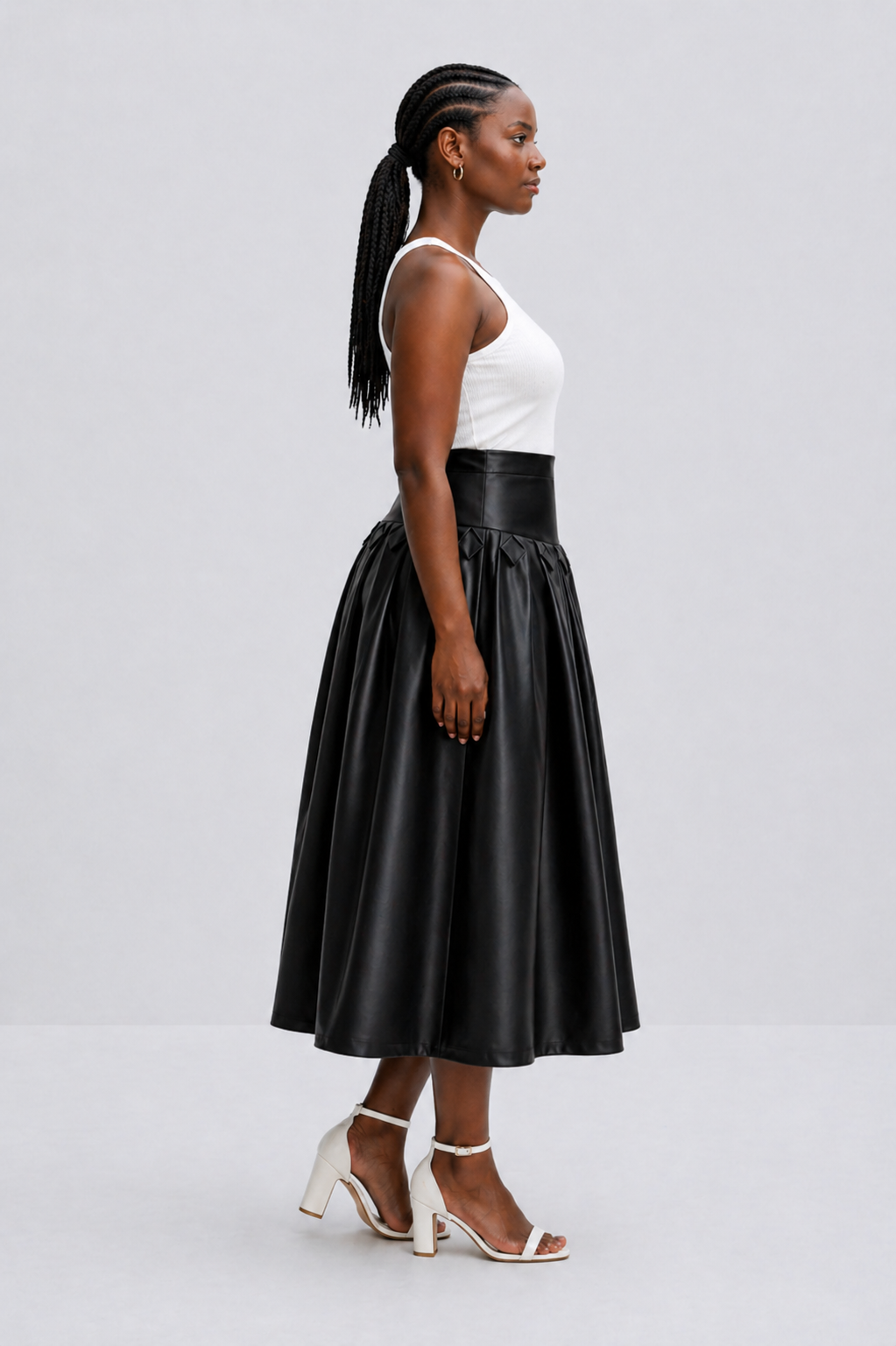 Woman wearing a black leather skirt and white top on a light gray background