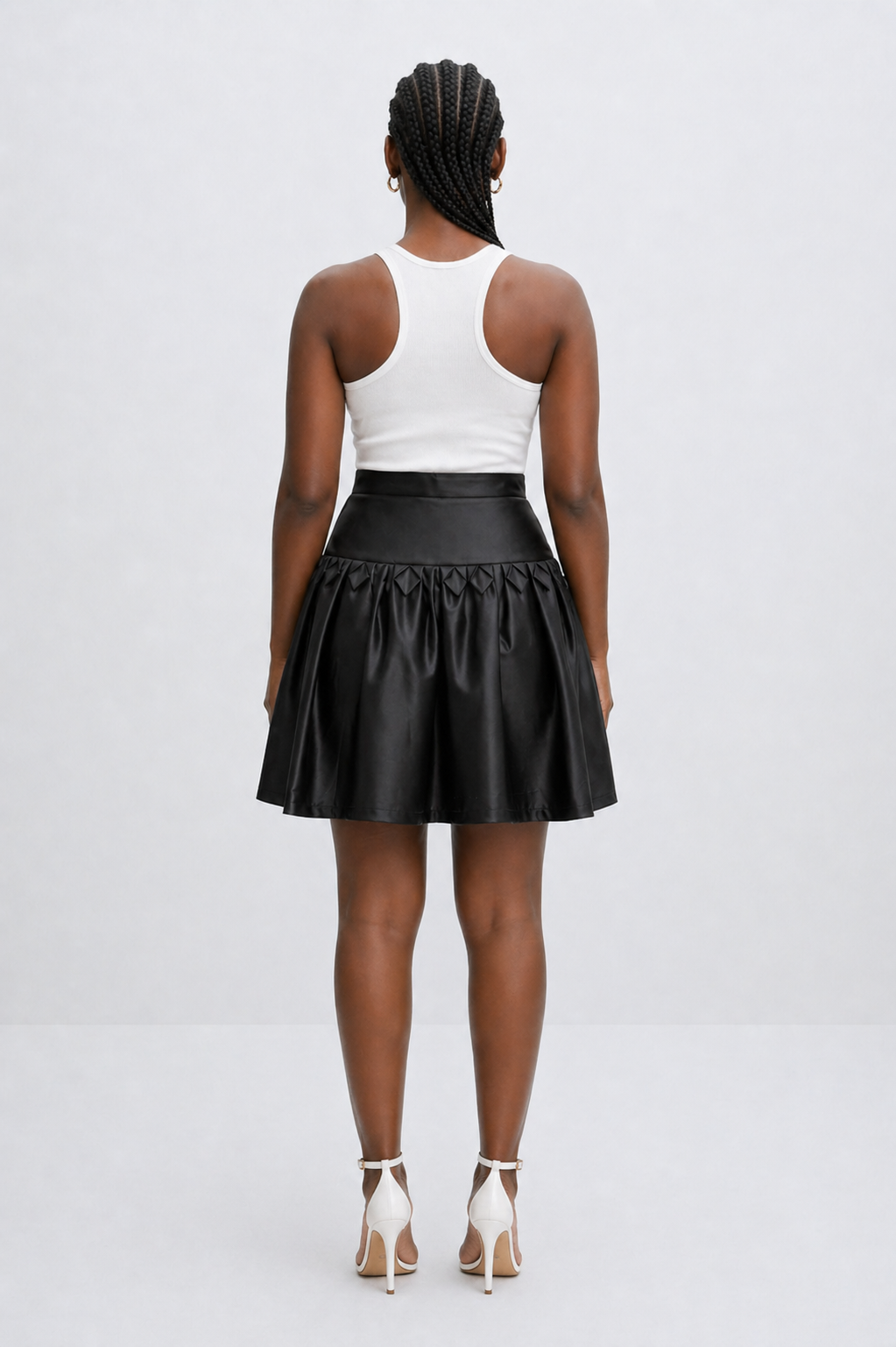 Person wearing a black leather skirt and white top on a white background