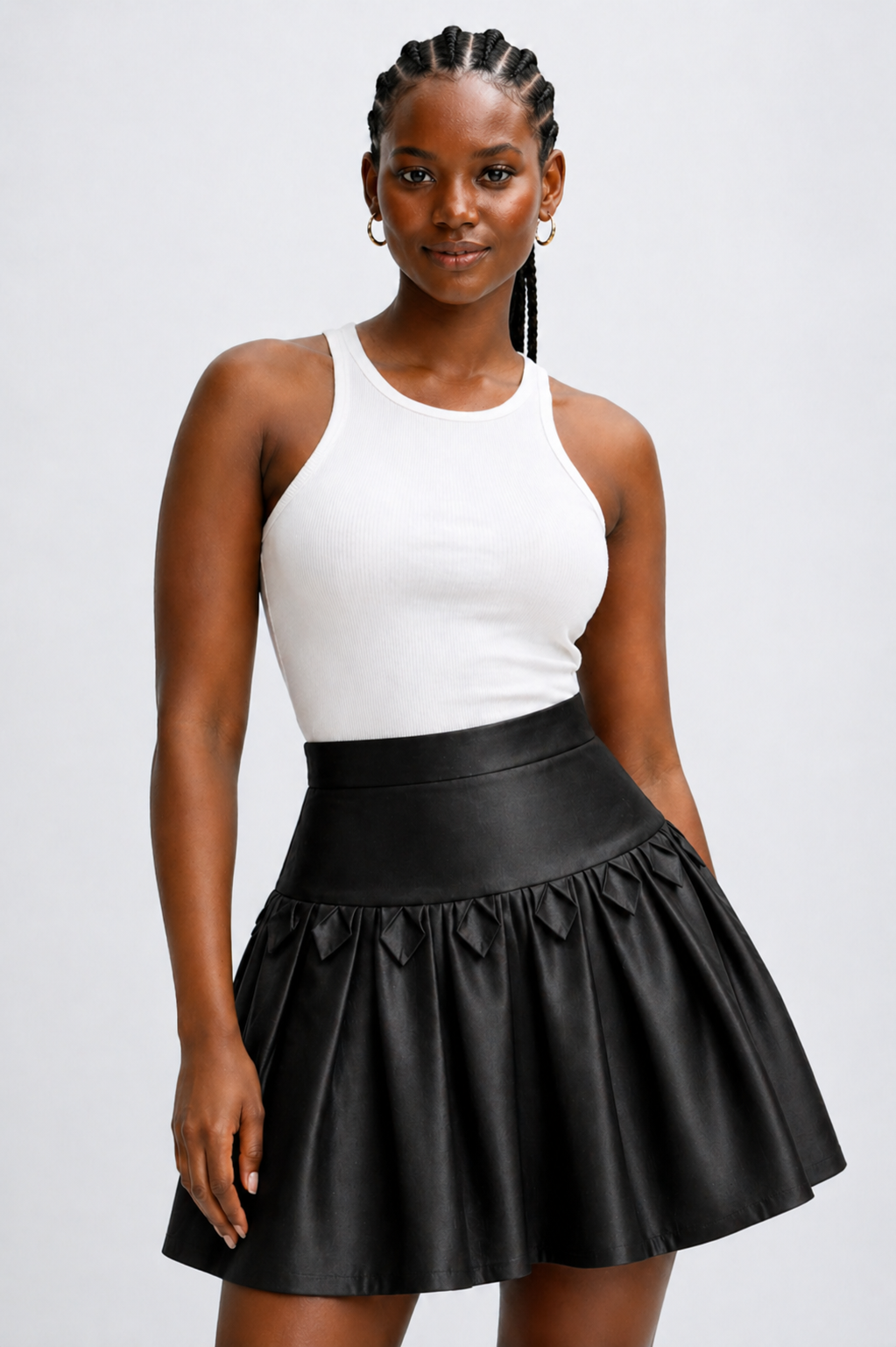Woman wearing a white tank top and black leather skirt on a plain background
