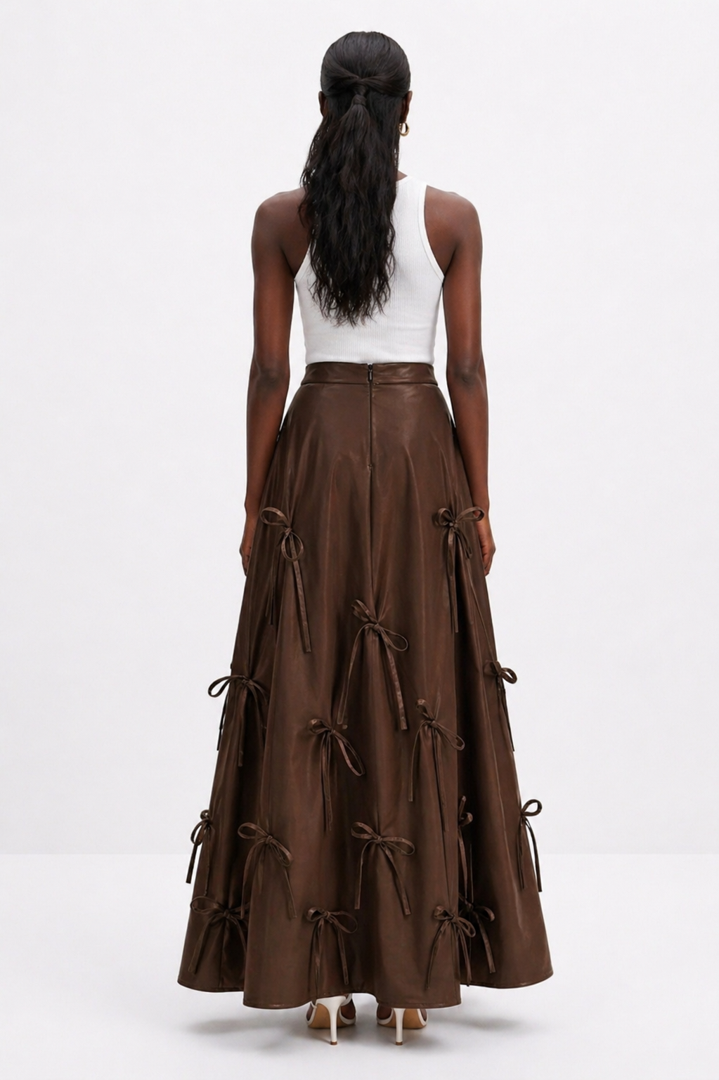Woman wearing a brown tiered skirt with a white top on a white background