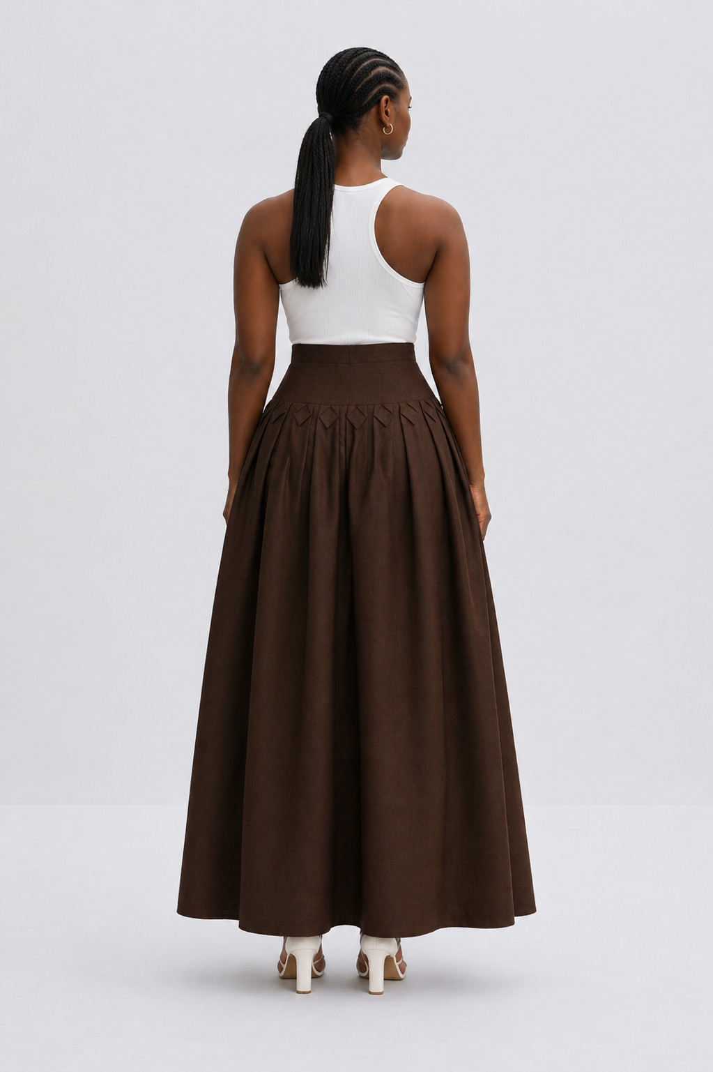Person wearing a white top and brown long skirt on a light gray background