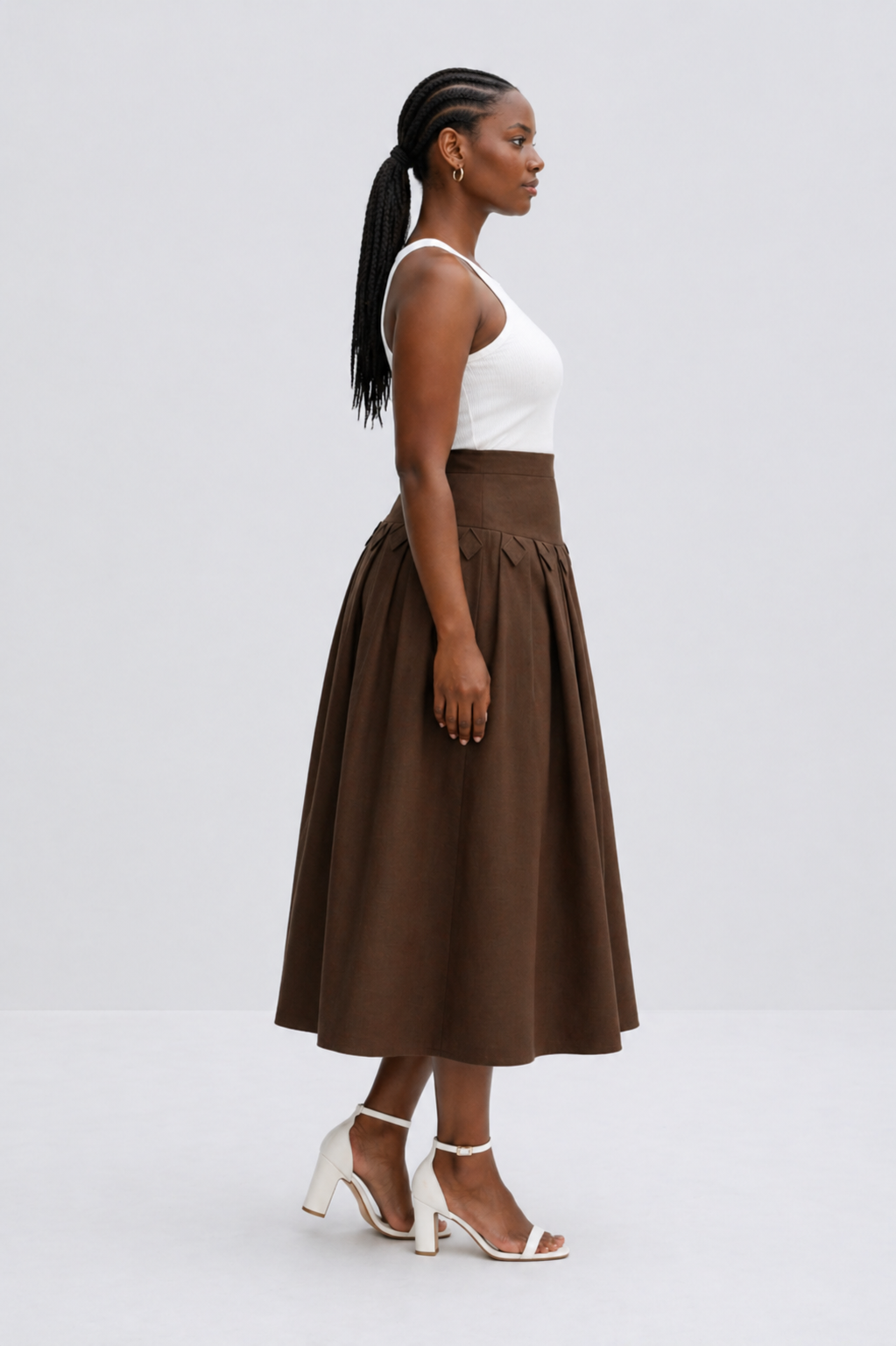 Woman wearing a brown skirt and white top on a light gray background