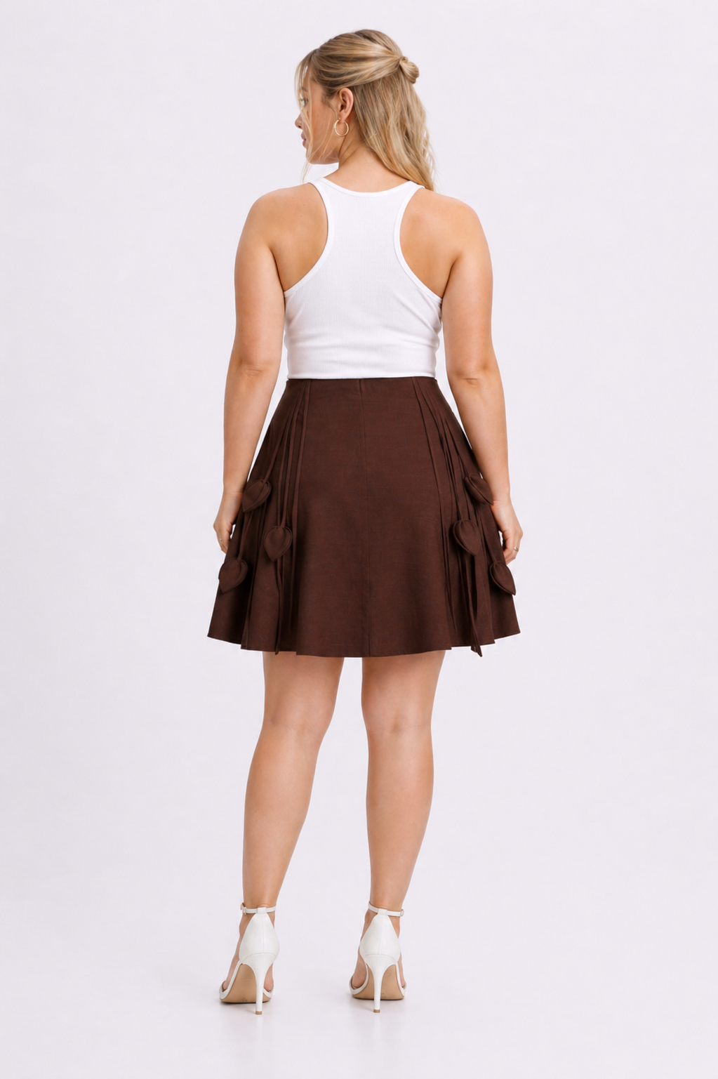 Woman wearing a white tank top and brown skirt on a white background