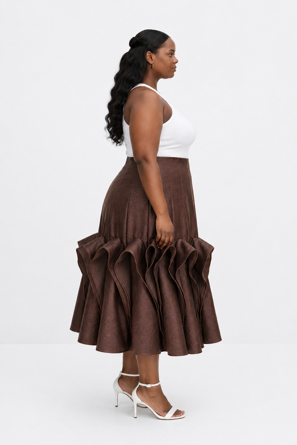 Woman wearing a brown ruffled skirt and white top on a white background