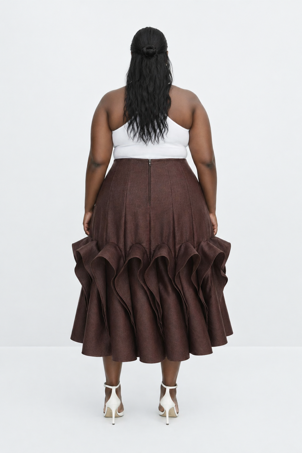 Woman wearing a brown ruffled skirt and white top on a white background