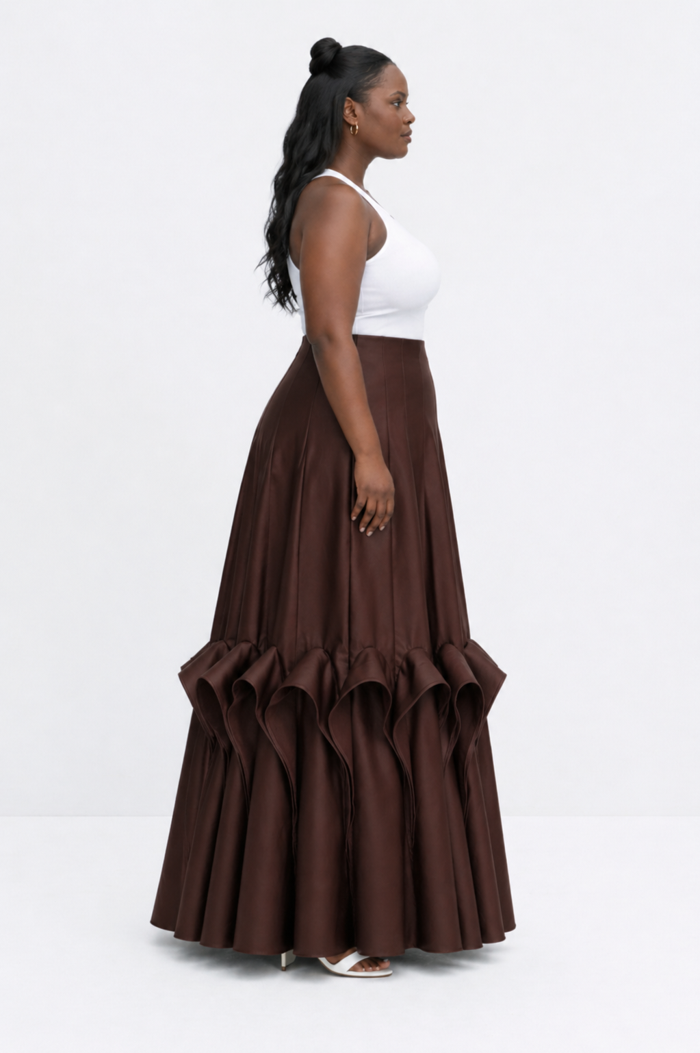 Woman wearing a brown ruffled skirt and white top on a white background