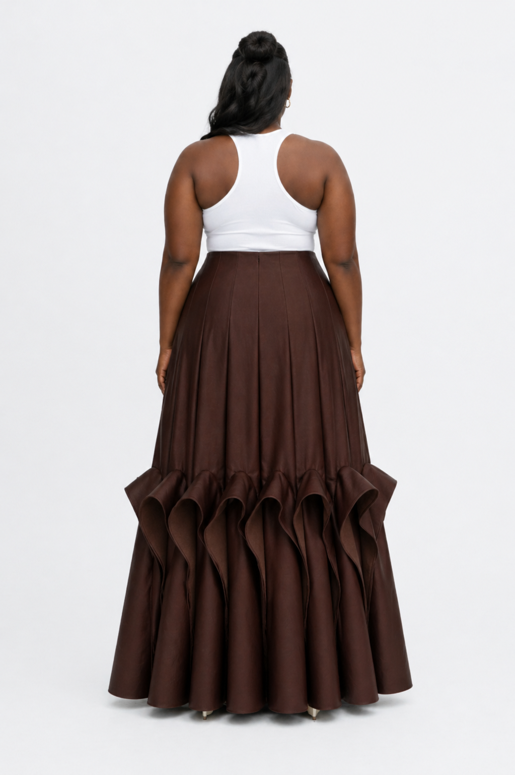 Person wearing a white top and brown ruffled skirt on a white background