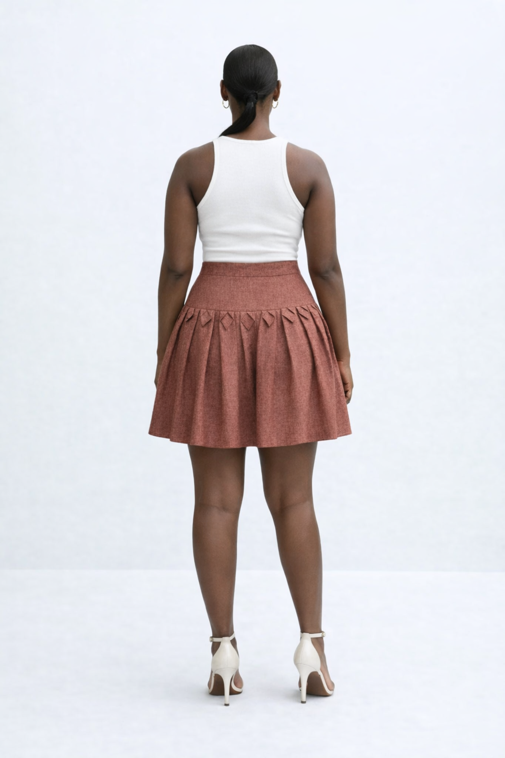 Woman wearing a white top and brown kingdom of daughters skirt on a white background
