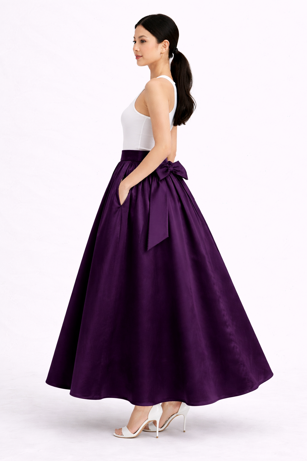 Woman wearing a long purple skirt with a white top on a white background